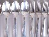 several forks and spoons are arranged in a row on a shelf