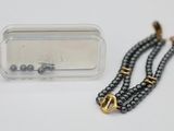 a black beaded necklace with a gold clasp and a clear case