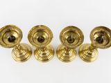 four brass candlesticks on a white background