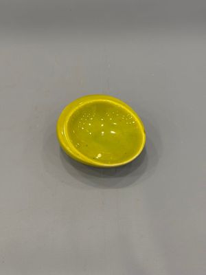 un bol jaune posé sur une table, avec une cuillère dedans