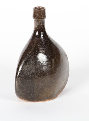 un vase brun posé sur une surface blanche