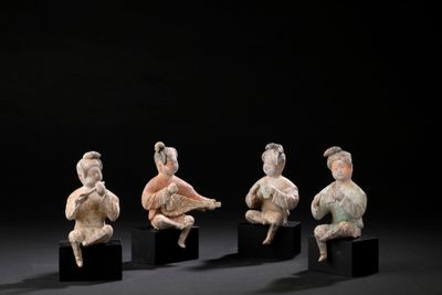 four figurines of people sitting on black blocks in front of a black background