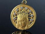 a close up of a gold pendant with a crown on top of it