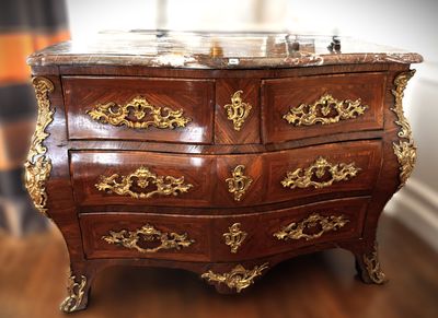 a marble top chest of drawers on a wooden floor