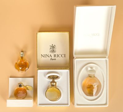 three perfume bottles in a white box on a beige surface