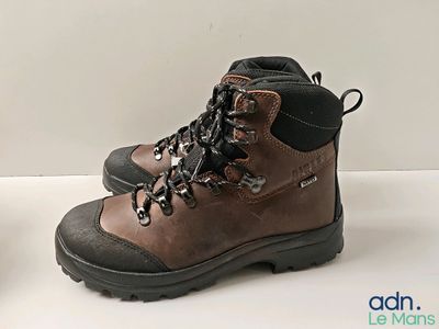 deux paires de chaussures de randonnée marron posées sur une surface blanche