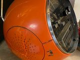 an orange clock sitting on top of a table next to a wall