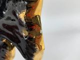 a black and gold statue of a dog on a green base