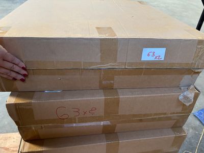 une personne tenant une pile de cartons posés sur une palette