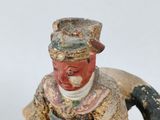 an old statue of a man sitting on a rock with a hat on