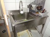 un évier dans un coin de la cuisine, avec une poubelle