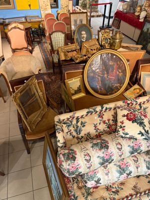 beaucoup de meubles dans une pièce où il y a beaucoup de tableaux accrochés aux murs