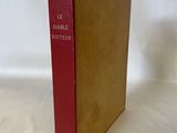 un vieux livre rouge posé sur une table blanche