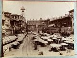 an old photo of a street with tables and umbrellas