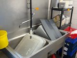 une cuisine équipée d'un évier, d'une poubelle et de poubelles