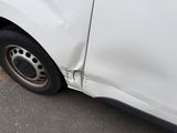 a white van that has been damaged and is parked on the side of the road
