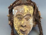 une image représentant un masque en bois avec des dreadlocks et un visage jaune