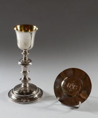 une coupe et une assiette en argent posées sur une surface blanche avec un fond gris
