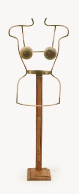 a metal sculpture of a face on a wooden stand