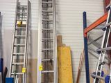 Plusieurs échelles sont alignées dans un garage, dont une appuyée contre le mur.