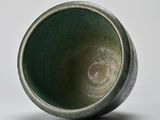 a close up of a green cup on a white surface