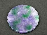 a close up of a purple and green stone on a black surface