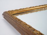 a mirror with a gold frame on a white wall