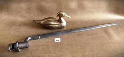 a small metal duck sitting next to a knife on a brown cloth
