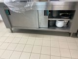 une grande cuisine en inox avec beaucoup de vaisselle sur le plan de travail