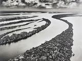 black and white photograph of a river with rocks in the middle