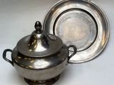 un plat en argent avec un couvercle en argent, à côté d'un bol en argent