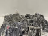 une pile de vêtements emballés dans des sacs en plastique posée sur une table