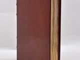 an old book with a brown cover sitting on top of a white surface