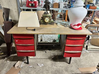 a red desk with two drawers and a lamp on top of it