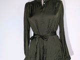 La robe est verte, elle a des manches longues et une ceinture.