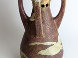 a brown vase with a bird on it on a white surface