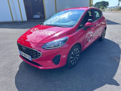 une Ford Fiesta rouge garée devant un immeuble