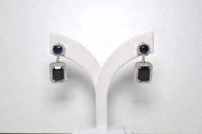 une paire de boucles d'oreilles en diamant noir et blanc posées sur un présentoir blanc
