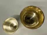 a gold cup and a silver cup on a white table