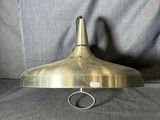 une vieille lampe à plaque en laiton, fixée à un support métallique, posée sur un canapé gris