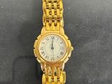 a gold wrist watch with roman numerals on it