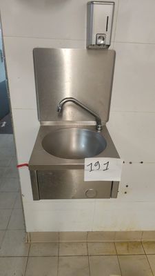 a stainless steel sink in a public restroom with a paper towel dispenser
