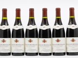 six bouteilles de vin sont alignées sur une surface blanche