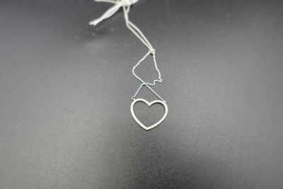 a close up of a silver necklace with a heart hanging from it