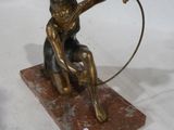 statue en bronze d'un garçon avec un cerceau sur une base en marbre