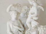 a statue of a group of people sitting on top of a vase