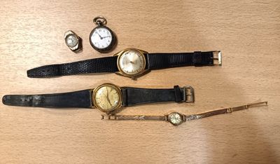 trois montres et un bracelet de montre posés sur une table en bois