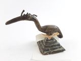 sculpture représentant un oiseau posé sur un socle, sur une surface blanche