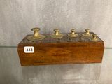 a wooden shelf with four brass candles on it