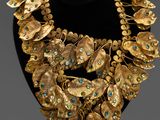 gold necklace with green and blue stones on a black mannequin